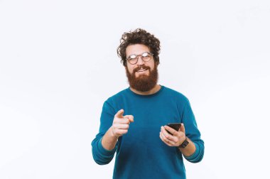 Kameraya işaret ve akıllı telefon tutarak mutlu gülümseyen sakallı adam