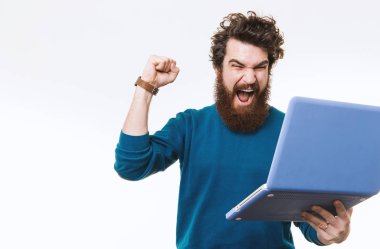 Hayret sakallı hippi adam clebrating başarı ve beyaz arka plan üzerinde atış studio laptop arıyorum