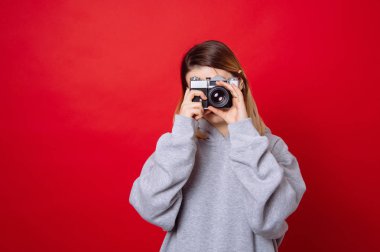 Kırmızı arka plan üzerinde duran ve eski vintage retro fotoğraf makinesi ile fotoğraf çekme genç moda kadın