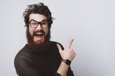 Hayret genç adam onun sol tarafında, sizin metin için yer işaret eden sakallı. Adam gözlük ve kahverengi kazak giyiyor.