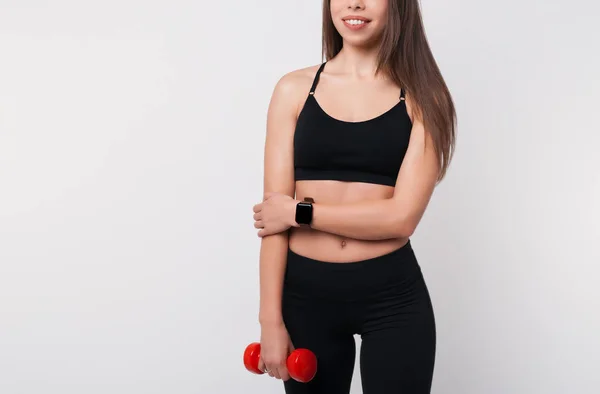 Portrait of pretty sporty girl holding weights. Fitness girl wearing smart watch