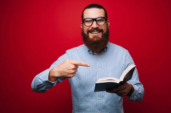Fröhlicher Bärtiger Mann Mit Brille Und Zeigt Auf Aufgeschlagenes Buch — Stockfoto