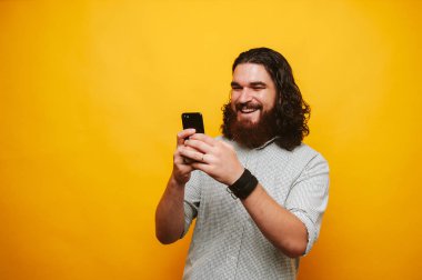 Gülümseyen sakallı hippi ve bir akıllı telefon kullanma