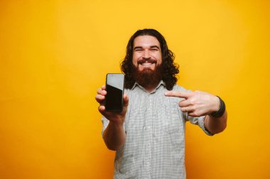 Uzun saçlı telefona işaret tişörtlü neşeli hipster adam