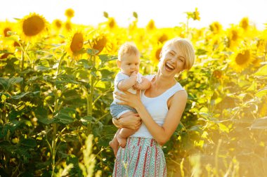 Neşeli anne ve küçük şirin bebeği ayçiçeği çevresinde