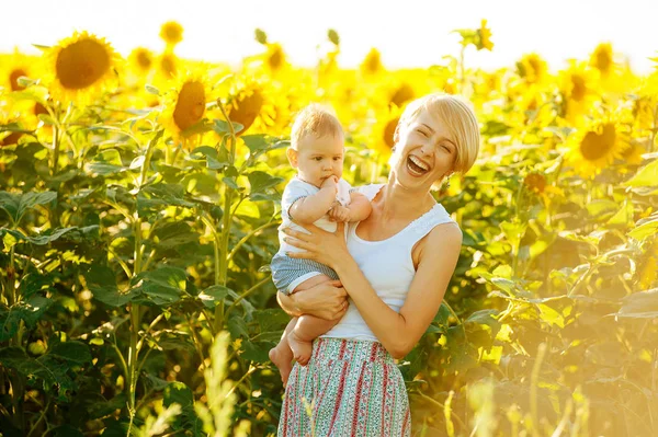 Neşeli anne ve küçük şirin bebeği ayçiçeği çevresinde