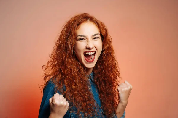 Happy winer young woman screaming. Curly red curly hair girl