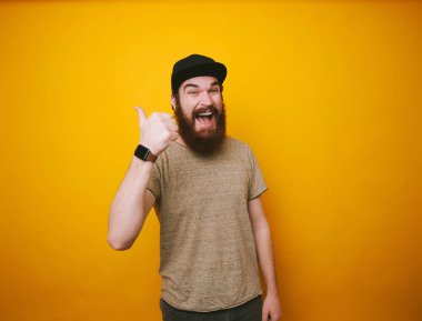 Heappy sakallı adamın şapka ve tshirt fotoğraf başparmak ile işaret