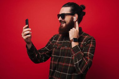 Rahat tarzı, kablosuz kulaklık kullanarak ve seyir vasıl hareket eden sakallı adam fotoğrafı