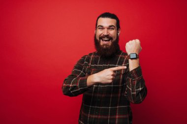 Mutlu gülümseyen sakallı adam poiting onun smartwatch olduğunu. 