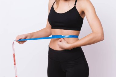 Beline ölçü bandı tarafından bir diyet sonra beyaz arka plan üzerinde ölçüm atletik ince kadın 