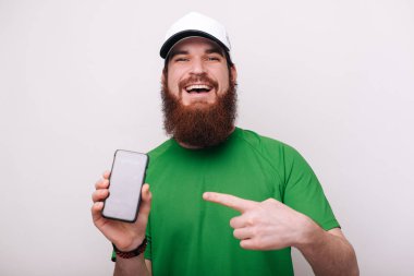 Kameraya bakarken smartphone ekranında işaret mutlu gülümseyen sakallı adam fotoğrafı 