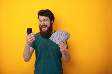 Sakallı adam cep telefonundan kumar mobil uygulama kullanarak bahis yaptıktan sonra zaferini kutluyor. 