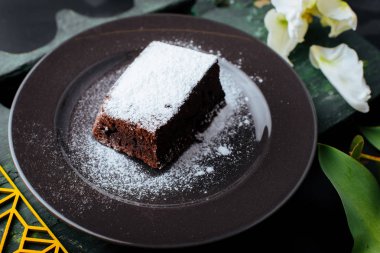 Krema şeker ahşap tablo ile karanlık plaka üzerinde çikolatalı pasta dilimi