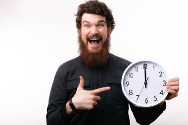Yakışıklı exicted beyaz saate geniş izole arka plan kameraya gülümseyen süre işaret eden adam sakallı 
