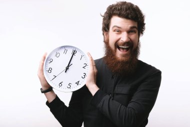 Genç adam büyük bir beyaz saat tutan sakallı. Portre izole beyaz zemin üzerine 