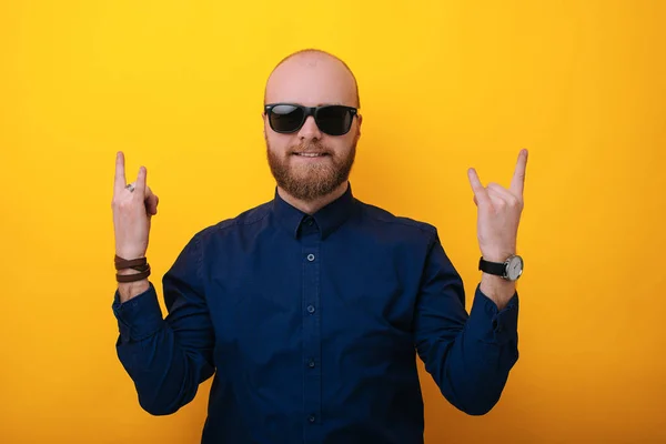 Like a rock star. Confident young man in sunglasses gesturing while standing against yellow background