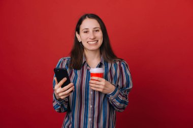 Genç ve güzel kadın Smartphone içinde rahat kıyafetler kırmızı renkli arka plan üzerinde kullanarak. 