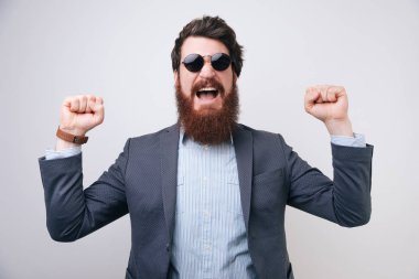 Genç yakışıklı adam deli ve başarı kollarını kaldırdı ve heyecanlı çığlık hayran kutluyor izole arka plan üzerinde güneş gözlüğü takıyor. Kazanan kavramı