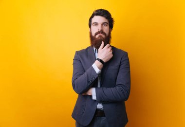 Adam konsantre yansıtır. İş adamı ayakta ciddi ve düşünme, üzerinde sarı arka plan 