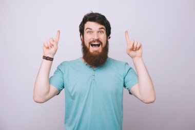 Casual tshirt ters iki elinizle işaret eden genç sürpriz yakışıklı sakallı adam portresi