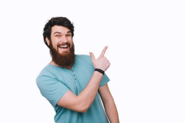 Yön gösteren ve gri arka plan üzerine parmağınızla işaret neşeli yakışıklı sakallı adam 