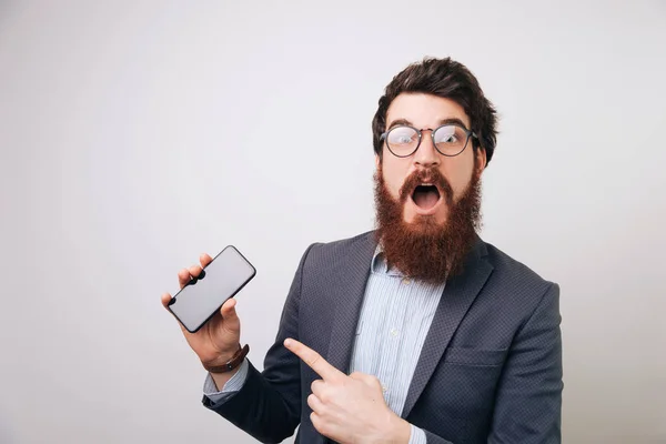 Empresario Barbudo Con Expresión Cara Impactada Apuntando Móvil Sobre Fondo — Foto de Stock