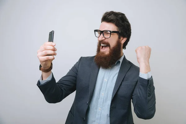 Empresário Barbudo Feliz Segurando Smartphone Celebrando Seu Sucesso Sobre Fundo — Fotografia de Stock