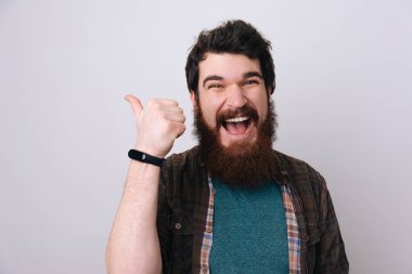 Çok heyecanlı sakallı adam memnun ve başparmak-up yukarıyı gösteren izole gri arka plan üzerinde 