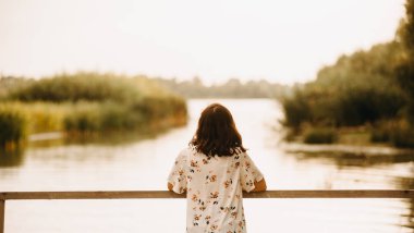 Genç bir kadın bir yaz günü bir nehir üzerinde gün batımını hayran 