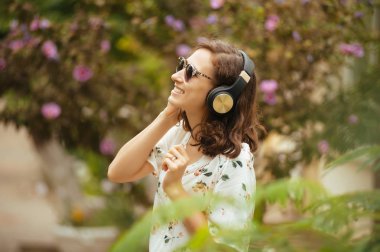 Kulaklık ve güneş gözlüğü açık havada güzel genç kadın. Müzik keyfi