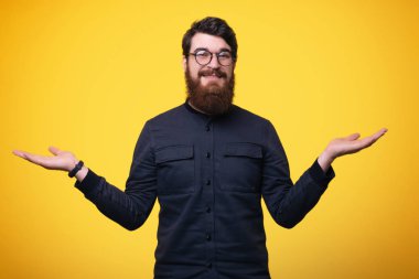 Gri gömlek ve gözlük, sakallı gülümseyen adam tutan eller izole sarı arka plan üzerinde ayağa kalkıp 