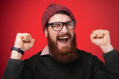 Şanslı genç hipster adam sakallı adam gözlük ve şapka giyen bir şey kazanmış gibi davranır. 