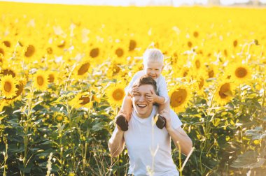 Fotoğrafı bir ayçiçeği alanında küçük oğlu ile eğleniyor neşeli sevgi dolu baba