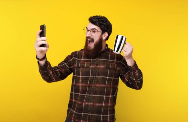 Genç adam selfie, bir fincan kahve ile tutarak heyecanlı alarak sakallı