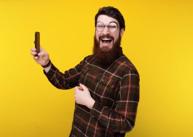 Mutlu gülümseyerek kameraya bakarken sellfie alarak yuvarlak gözlüklü adam sakallı