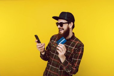 Sunglasss ve kareli gömlek serin yenilikçi mobil whilw onun yeni crdit kart gösterilen kullanıyor