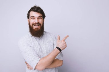 Uzağa işaret ve kameraya bakarak yakışıklı gülümseyen sakallı adam portresi 