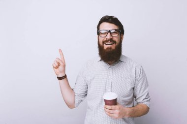 Genç bir fincan kahve el ve parmak ile işaret çok mutlu içme sakallı adam akıllı