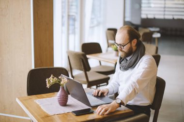 Genç yakışıklı adam küçük bir kafede otururken onun iş günü başlamak üzere sakallı.