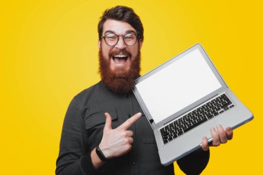 Mutlu sakallı adam gözlük tutan ve pointintg laptop fotoğraf makinesi ararken 
