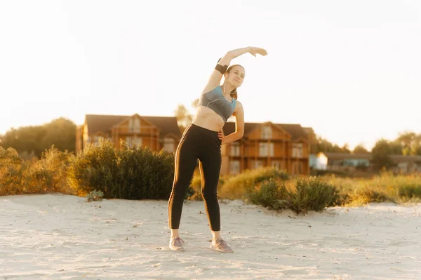 Beautiful view of woman doing yoga stretching on beach view at sunset