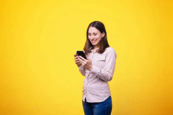 Mulher Bonita Usando Seu Smartphone Beber Café Sobre Fundo Amarelo — Fotografia de Stock