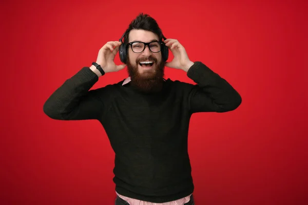 Joven Barbudo Escuchando Música Con Auriculares Sobre Fondo Rojo —  Fotos de Stock