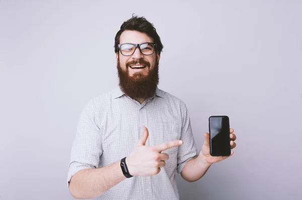 Bild Skäggig Man Pekar Finger Smartphone Inne Och Smilig Kamera — Stockfoto