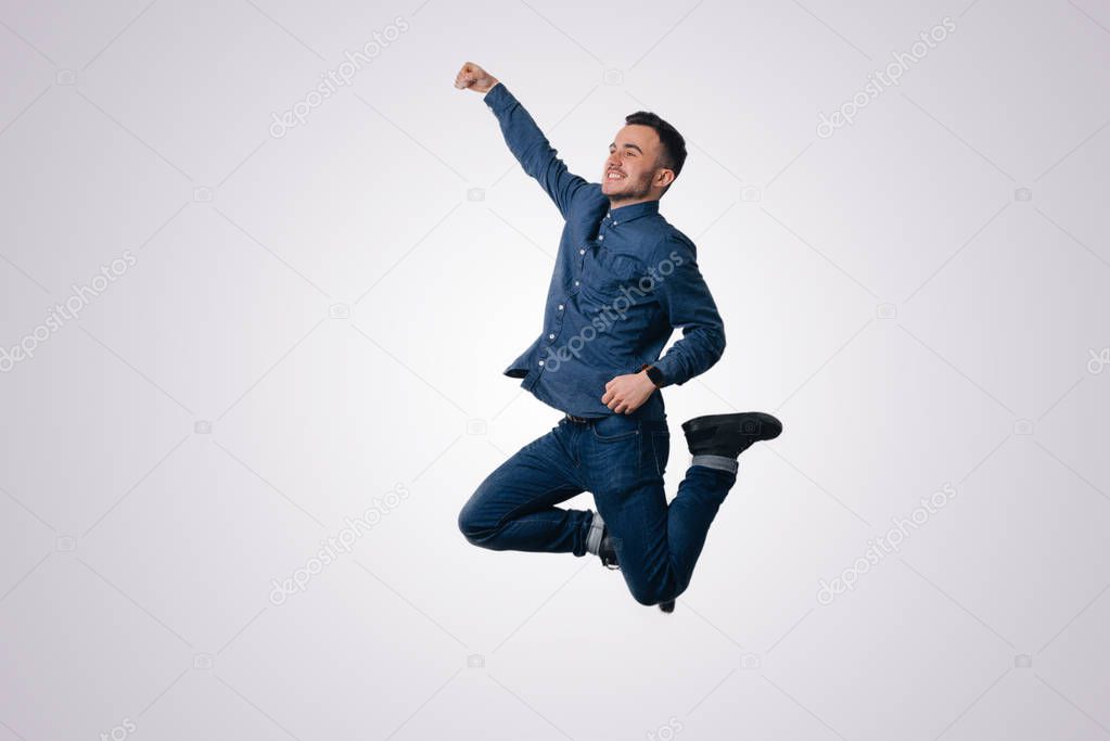 Happy excited cheerful young man jumping and celebrating success over white background