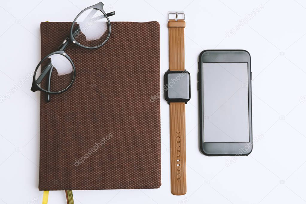 Minimalistic work place with notebook, glasses, smartwatch and smartphone