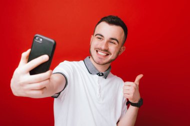 Neşeli genç çocuk seflie fotoğraf yapıyor ve başparmak yukarıya el hareketi