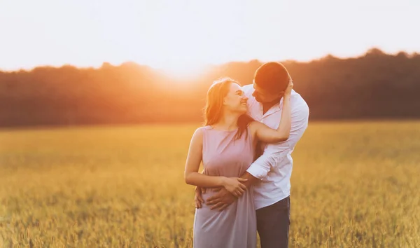 男性女性を後ろから抱き締めると夕日の自然の中 互いに見て カップル写真 — ストック写真