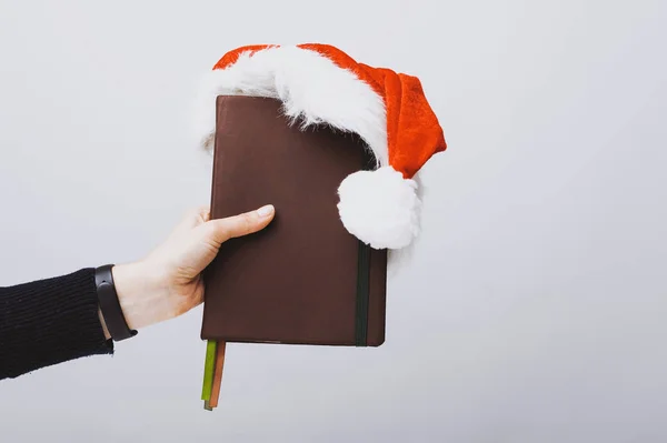 Hand Holding Book Agenda Red Christmas Hat White Background — Stock Photo, Image